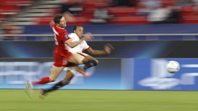Penyerang Bayern Munchen, Robert Lewandowski membawa bola dari kejaran pemain Sevilla, Fernando pada pertandingan Piala Super Eropa di Budapest, Hongaria, Kamis (24/9/2020). Munchen menang tipis 2-1 atas Sevilla. (AP Photo/Laszlo Balogh)