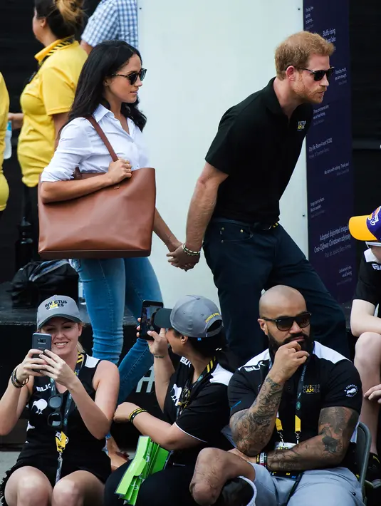 Pangeran Harry dan kekasihnya Meghan Markle bergandengan tangan saat menghadiri Invictus Games 2017 di Toronto, Kanada, Senin (25/9). Untuk kali pertama, keduanya menunjukkan kemesraan di depan publik. (Nathan Denette/The Canadian Press via AP)