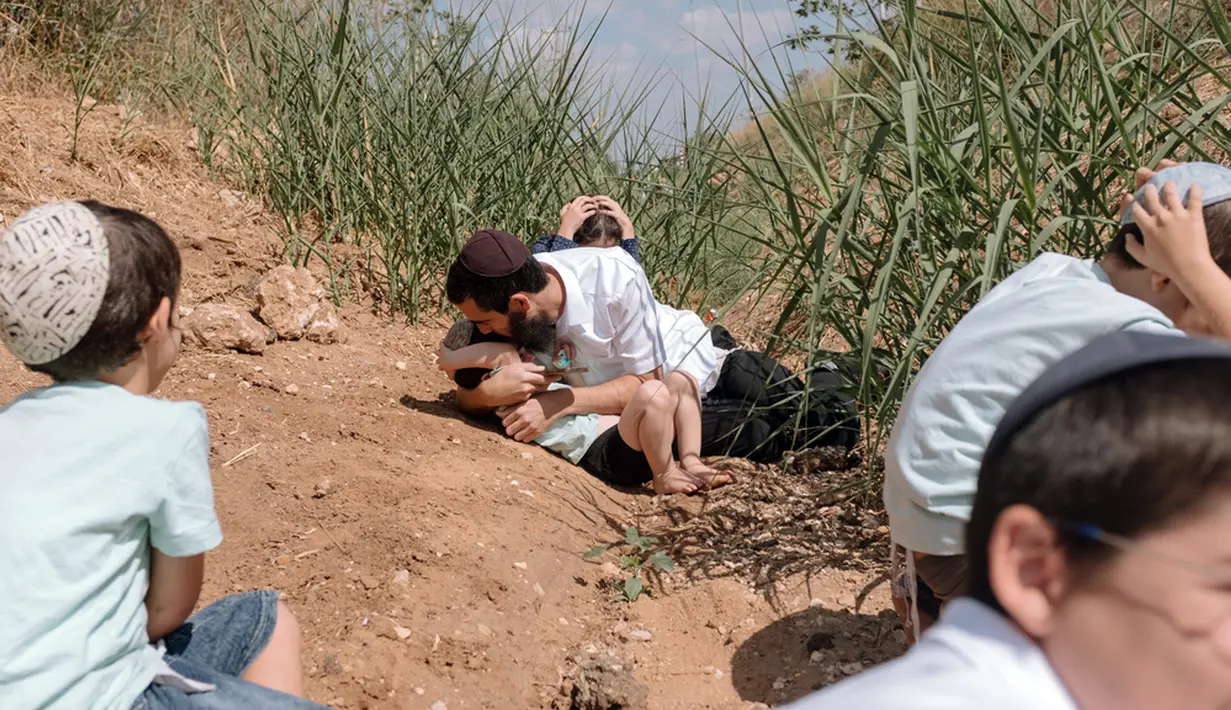 Warga Israel berlindung saat sirene membunyikan peringatan akan adanya roket yang ditembakkan dari Jalur Gaza di Rehovot, Israel, Jumat (13/10/2023). (AP Photo/Dor Kedmi)