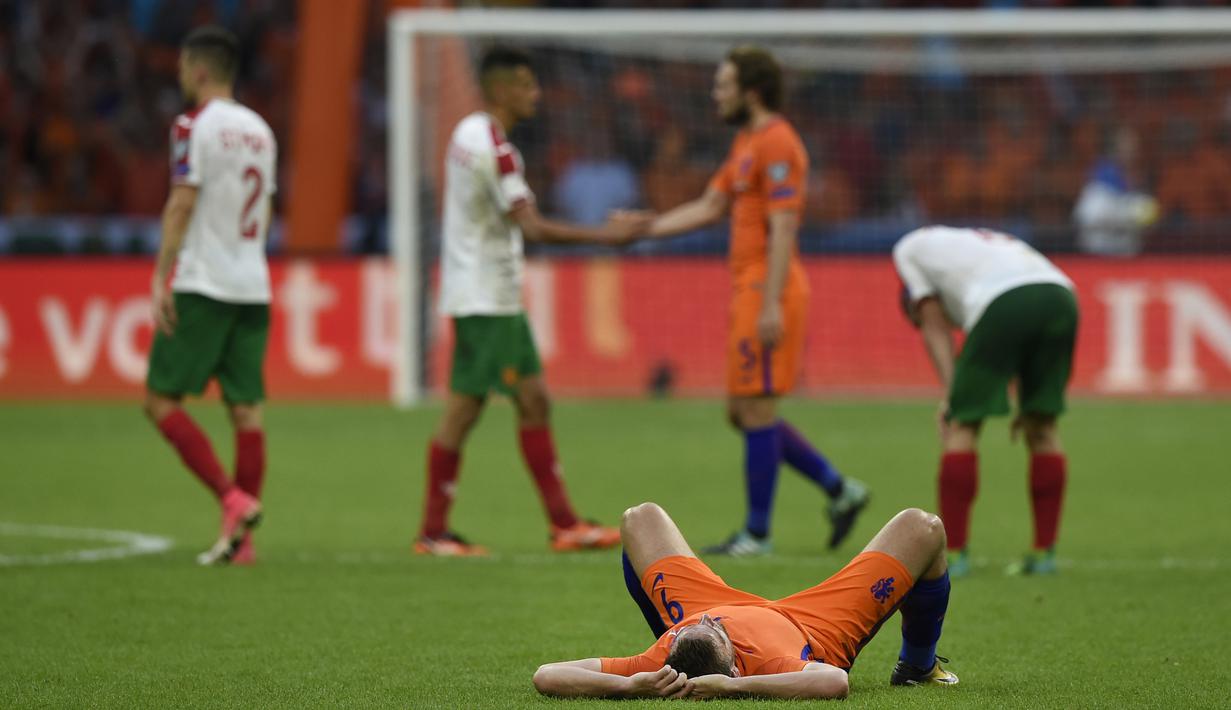 Penyerang Belanda, Vincent Janssen menikmati kemenangan atas Bulgaria di atas dengan berbaring di atas rumput pada laga grup A kualifikasi Piala Dunia 2018 di Amsterdam, (3/9/2017). Belanda menang 3-1. (AFP/John Thys)