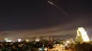 Tembakan rudal mewarnai langit ketika serangan udara koalisi Barat diarahkan ke ibu kota Damaskus, Suriah, Sabtu (14/4). Pemerintah AS, Inggris, dan Prancis memutuskan untuk melakukan serangan militer terhadap rezim Bashar al-Assad. (AP/Hassan Ammar)