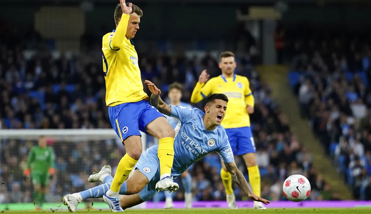 Pemain Manchester City Joao Cancelo (kanan) dilanggar oleh pemain Brighton and Hove Albion Lewis Dunk pada pertandingan sepak bola Liga Inggris di Etihad Stadium, Manchester, Inggris, 20 April 2022. Manchester City menang 3-0. (AP Photo/Dave Thompson)