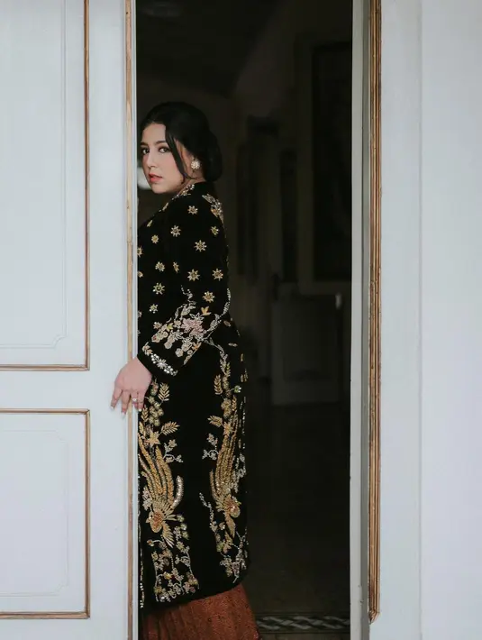 Nessie Judge tampil anggun dengan kebaya kutu baru velvet hitam emas. Dipadukan dengan kain batik wiru bernuansa cokelat gelap dan obi merah. [@nessiejudge]