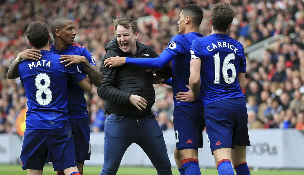 Seorang fans masuk ke lapangan usai gelandang Manchester United, Jesse Lingard, membobol gawang Middlesbrough. Tak hanya selebrasi flute, suporter masuk ke lapangan menjadi hal menarik lain yang mewarnai kemenangan 3-1 Setan Merah. (AP/Nigel French)