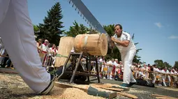Peserta menggergaji batang pohon dengan "tronza", gergaji tradisional daerah Basque, pada hari ketiga festival San Fermin di Pamplona, Spanyol, Senin (8/7/2019). Festival San Fermin menghadirkan beberapa olahraga pedesaan Basque seperti menggergaji dan memotong pohon dengan kapak. (JAIME REINA/AFP)