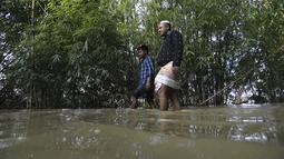 Orang-orang mengarungi jalan yang banjir di daerah Kanaighat di Sylhet, Bangladesh (23/5/2022). Banjir bandang pra-musim telah membanjiri bagian dari India dan Bangladesh, menewaskan sedikitnya 24 orang dalam beberapa pekan terakhir dan mengirim 90.000 orang ke tempat penampungan. (AP Photo)