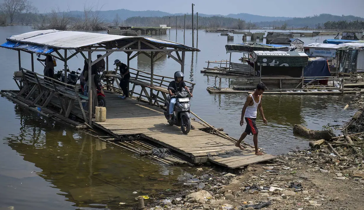Warga mengarahkan rakit penyeberangan ke tepi bendungan  yang menyusut di dekat Kampung Somang di Lebak, Banten, Kamis (30/7/2026). (AFP/ Bay Ismoyo)