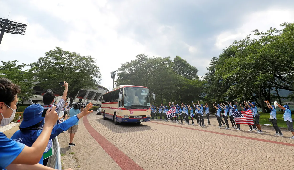 Sejumlah relawan bersorak saat bus yang membawa pemain softball Ameria Serikat meninggalkan Stadion Bisbol Fukushima Azuma setelah pertandingan putaran pembukaan softball Olimpiade Tokyo 2020 antara Italia melawan Amerika Serikat di Fukushima, Jepang, pada 21 Juli 2021. (AFP/Kazuhiro Fujihara)