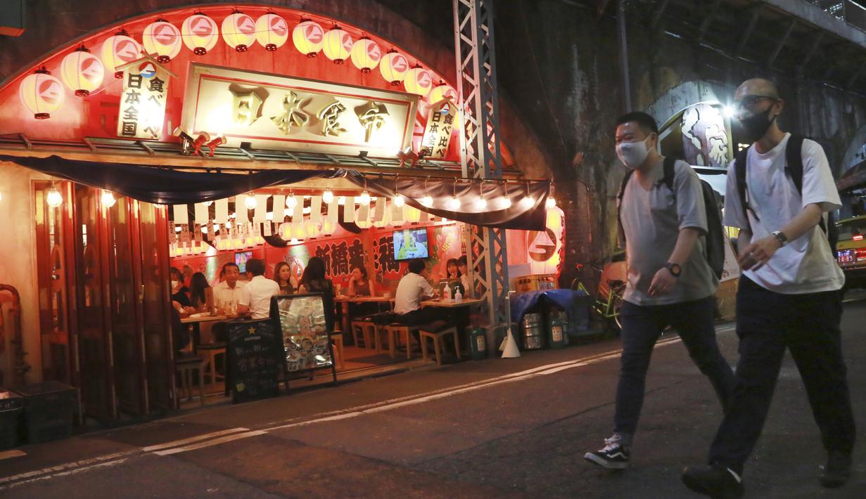Orang-orang yang memakai masker berjalan di sepanjang jalan selama keadaan darurat di Tokyo, Jepang pada Senin (12/7/2021). Status darurat keempat di Tokyo ini, yang berlaku hingga 22 Agustus, akan mencakup durasi gelaran Olimpiade Tokyo. (AP Photo/Koji Sasahara)
