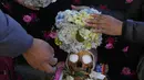 Orang-orang menghias tengkorak manusia dengan bunga di pemakaman umum selama festival tahunan "Natitas" di La Paz, Bolivia, Senin (8/11/2021). Dalam festival ini warga ramai-ramai menghias tengkorak leluhur mereka dengan berbagai dekorasi mulai dari bunga, topi hingga kacamata (AP Photo/Juan Karita)