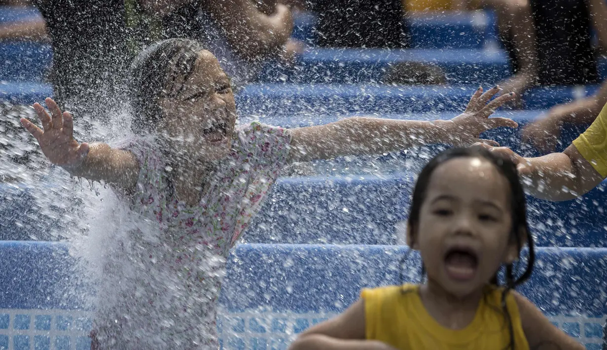 Ekspresi anak-anak saat bermain di kolam portabel yang diberikan oleh pemerintah setempat mendinginkan tubuh pada saat musim panas di Manila, Filipina (12/4). (AFP Photo/Noel Celis)