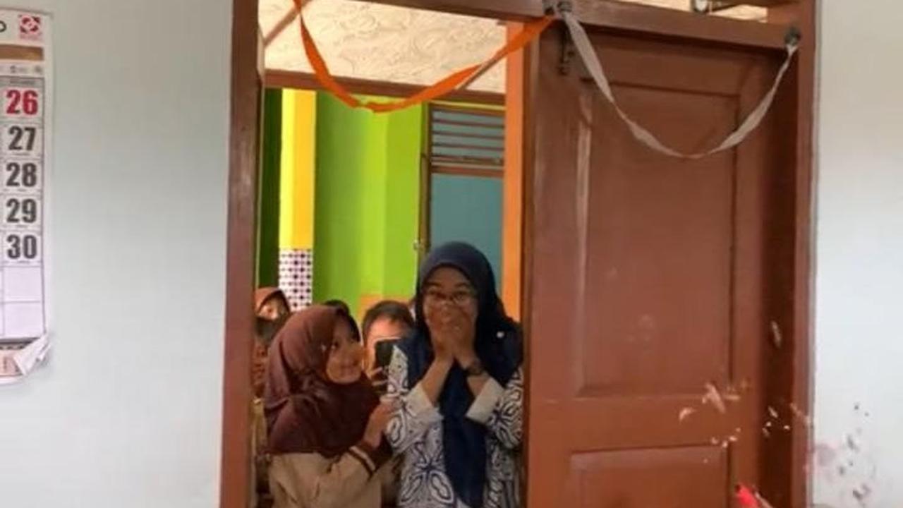 Saat pintu di buka dari luar oleh anak-anak perempuan, ibu guru ini pun tampak kaget Ia seolah tak menyangka akan dapat kejutan dari murid-muridnya.