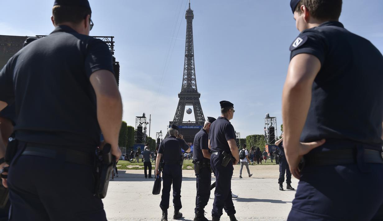 Sejumlah polisi melakukan penjagaan jelang acara Champs de Mars yang digelar untuk menyambut Piala Eropa 2016 di Paris fan zone, belakang Menara Eiffel, Prancis, Jumat (10/6/2016). (AFP/Alain Jocard)