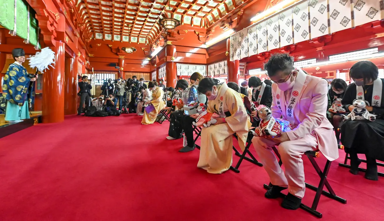 Pemilik robot peliharaan Sony Aibo mengambil bagian dalam upacara doa untuk merayakan ulang tahun ketiga Aibo dan berharap kesehatan yang baik pada masa depan di Kuil Kanda, Tokyo, Jepang, Jumat (12/11/2021). (Kazuhiro NOGI/AFP)