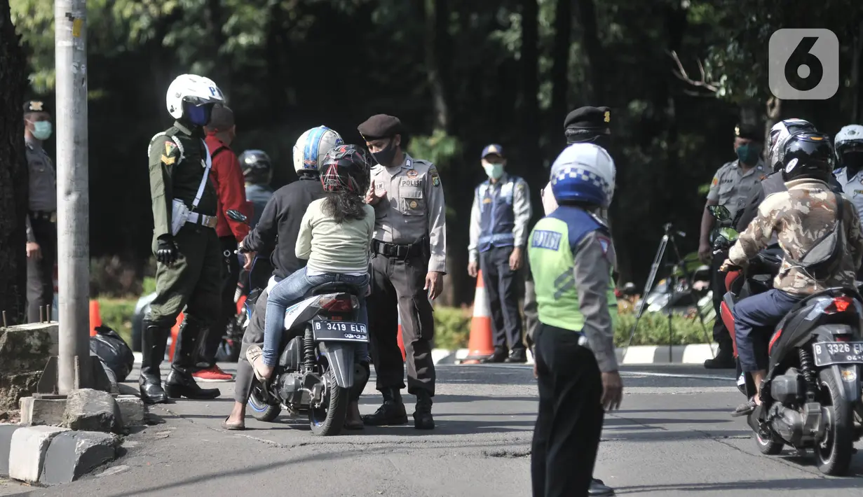 Petugas kepolisian memeriksa identitas pengendara motor yang berpenumpang saat penerapan Pembatasan Sosial Berskala Besar (PSBB) di Jalan Akses UI, Depok, Jawa Barat, Rabu (15/4/2020). PSBB di kota Depok yang resmi berlaku hari ini berlangsung selama 14 hari. (merdeka.com/Iqbal S Nugroho)