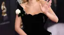 Penyanyi Rita Ora menyematkan mawar putih pada gaunnya saat berjalan di karpet merah Grammy Awards 2018, New York, Minggu (28/1). Mereka memilih warna putih untuk mendukung MeToo, gerakan melawan pelecehan seksual (Dimitrios Kambouris/GETTY IMAGES/AFP)