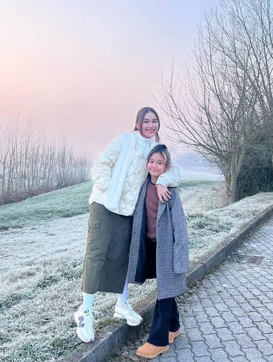 OOTD winter look dari Ayu Ting Ting dan Bilqis. Ayu Ting Ting tampil cantik dengan puffer jacket putih dan midi cargo skirt hijau, dipadu syal, kaus kaki panjang, dan sneakers putih. Sedangkan Bilqis dengan atasan cokelat ditumpuk long coat abu-abu, celana panjang hitam, dan alas kaki cokelat. [Foto: Instagram/ayutingting92]