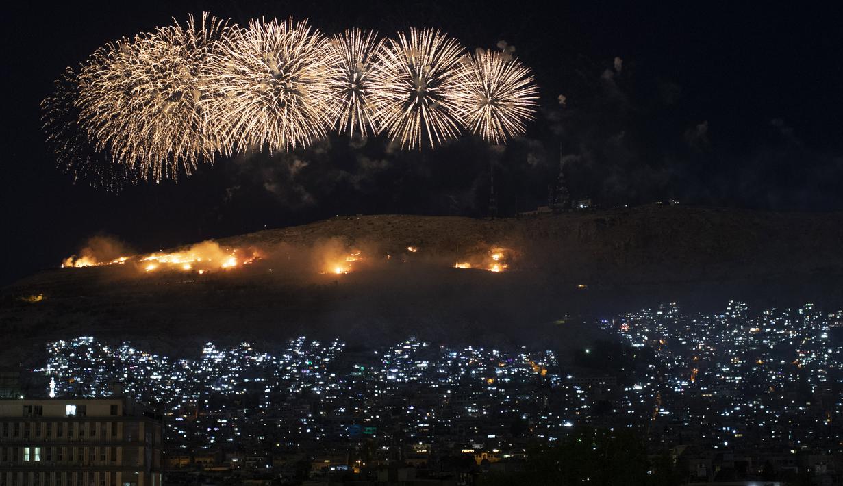 Kembang api meledak di atas Gunung Qasioun saat para pendukung merayakan kembali terpilihnya Presiden Suriah Bashar Assad di Damaskus, Kamis (27/5/2021). Bashar al-Assad terpilih kembali untuk masa jabatan keempat sebagai presiden Suriah yang dilanda perang. (AP Photo/Hassan Ammar)
