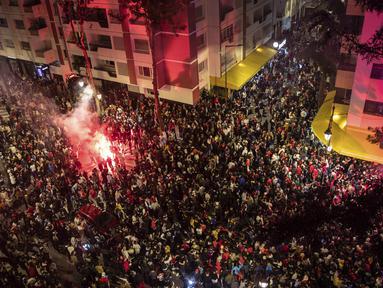 Ribuan warga Maroko berkumpul merayakan kemenangan Maroko atas Spanyol dalam pertandingan Piala Dunia 2022, di Rabat, Maroko, Selasa (6/12/2022). Meski Spanyol menguasai bola lebih banyak namun tidak mendapatkan peluang untuk membobol gawang Maroko. (AP Photo/Mosa’ab Elshamy)
