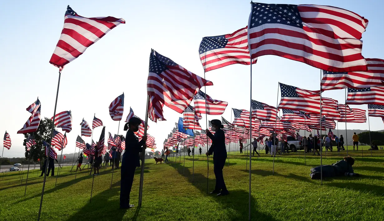 Orang-orang membantu pengibaran bendera AS untuk peringatan 20 tahun serangan 9/11 di Pepperdine University di Malibu, California, Rabu (8/9/2021). Selama 14 tahun, universitas itu memperingati tragedi 11 September 2001 dengan mengibarkan sekitar 3.000 bendera Amerika. (Frederic J. BROWN/AFP)