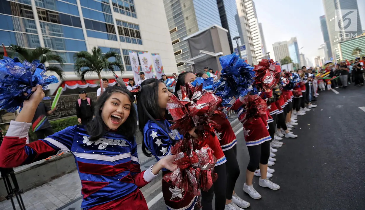 Pemandu sorak memeriahkan prosesi Torch Relay Asian Games 2018 di Jakarta, Sabtu (18/8). Hari ini merupakan puncak kirab obor Asian Games 2018 dimana api abadi akan berlabuh di Gelora Bung Karno (Liputan6.com/Faizal Fanani)