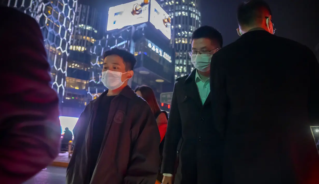 Komuter yang mengenakan masker berjalan melintasi persimpangan di Beijing, Rabu (2/11/2022). Para pekerja iPhone Apple Inc meninggalkan pabrik karena lokasinya berada dalam zona industri Kota Zhengzhou yang sedang diberlakukan lockdown setelah adanya 64 laporan kasus virus corona di kawasan tersebut. (AP Photo/Mark Schiefelbein)