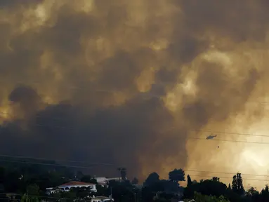 Sebuah helikopter meluncurkan air saat saat api menjalar di dekat daerah perumahan, di Alhaurin de la Torre, Malaga, Spanyol, Sabtu (16/7/2022). Kebakaran hutan terus menyebar ke seluruh Spanyol ketika petugas pemadam kebakaran bekerja untuk mengendalikan api. (AP Photo/Gregorio Marrero)