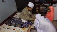 Seorang perempuan Thailand mencium tangan suaminya setelah salat di ruang tamu rumah mereka di Bangkok, 28 April 2020. Banyak tempat ibadah ditutup guna membendung penyebaran Virus Corona COVID-19 ketika Umat Muslim di seluruh dunia menyambut bulan suci Ramadan. (AP Photo/Gemunu Amarasinghe)