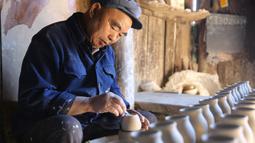 Seorang perajin bekerja di bengkel pembuatan tembikar di Desa Wanyao, Mazhan, Tengchong, Provinsi Yunnan, China, 18 November 2020. Para perajin di desa ini menggunakan tanah liat lokal yang unik dan mengikuti proses tradisional dalam membuat berbagai produk tembikar. (Xinhua/Liang Zhiqiang)