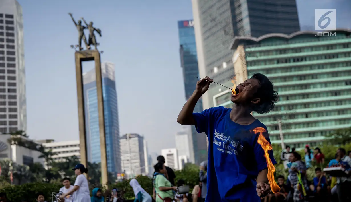 Seorang pria melakukan atraksi menelan api di area Car Free Day kawasan MH Thamrin, Jakarta, Minggu (4/6). Pria yang tergabung dalam kelompok seniman Kuda Lumping tersebut melakukan aksi berbahaya untuk mencari nafkah. (Liputan6.com/Faizal Fanani)