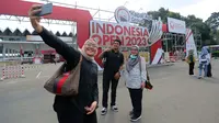 Sejumlah pengunjung melakukan swafoto di pintu gerbang Istora Senayan menjelang Indonesia Open 2023 pada Senin (12/06/2023). Ketua Panpel Armand Darmadji mengungkapkan bahwa tahun ini akan menjadi edisi terakhir turnamen BWF Super 1000 tersebut di Istora Senayan sebelum dipindahkan ke arena yang lebih besar yakni Indoor Multifunction Stadium. (Bola.com/Bagaskara Lazuardi)