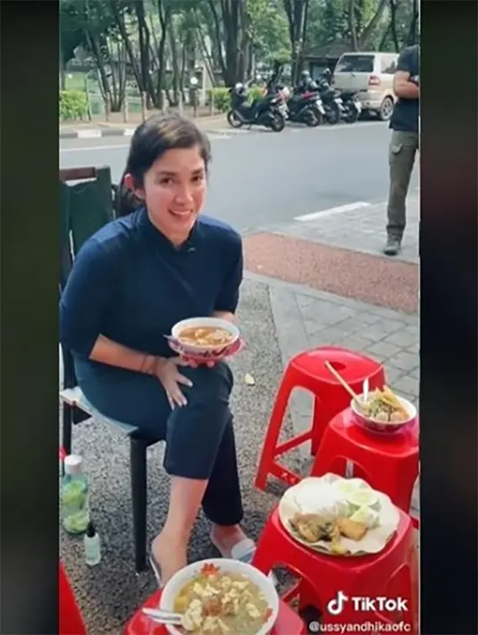 Gaya santai Ussy saat menikmati makanan kaki lima pinggir jalan. Perempuan kelahiran Jakarta 42 tahun silam itu juga kerap membawa anak-anaknya makan mie ayam hingga bakso yang jadi langganannya. [Tiktok]