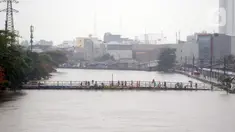 Warga berdiri di salah satu jembatan penghubung Banjir Kanal Barat di Kawasan Tanah Abang, Jakarta, Rabu (1/1/2020). Hujan yang mengguyur Jakarta sejak Selasa sore (31/12/2019) mengakibatkan debit air Banjir Kanal Barat tinggi dan hampir meluap. (Liputan6.com/Helmi Fithriansyah)