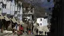 Orang-orang berjalan-jalan di kota Gjirokastra, Albania selatan pada 5 Februari 2021. Pariwisata telah berkembang di kota Gjirokastra, yang diakui sebagai Situs Warisan Dunia UNESCO, tetapi pandemi virus corona menghentikannya secara tiba-tiba. (AP Photo/Hektor Pustina)