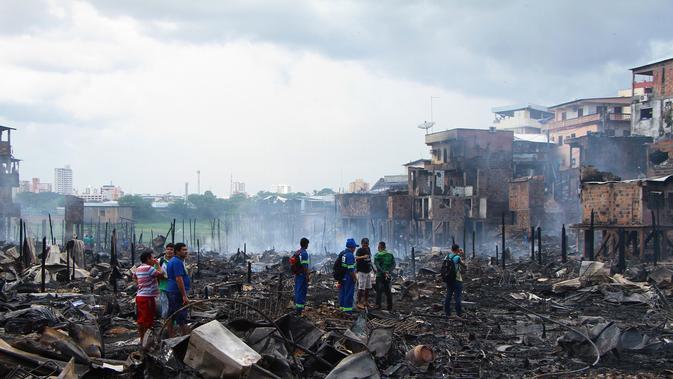 Sejumlah warga melihat sisa-sisa rumah yang hangus di lingkungan Educandos di Manaus, Brasil (17/12). Para pihak berwenang mengatakan setidaknya 600 rumah kayu hangus terbakar. (AP Photo/Edmar Barros)