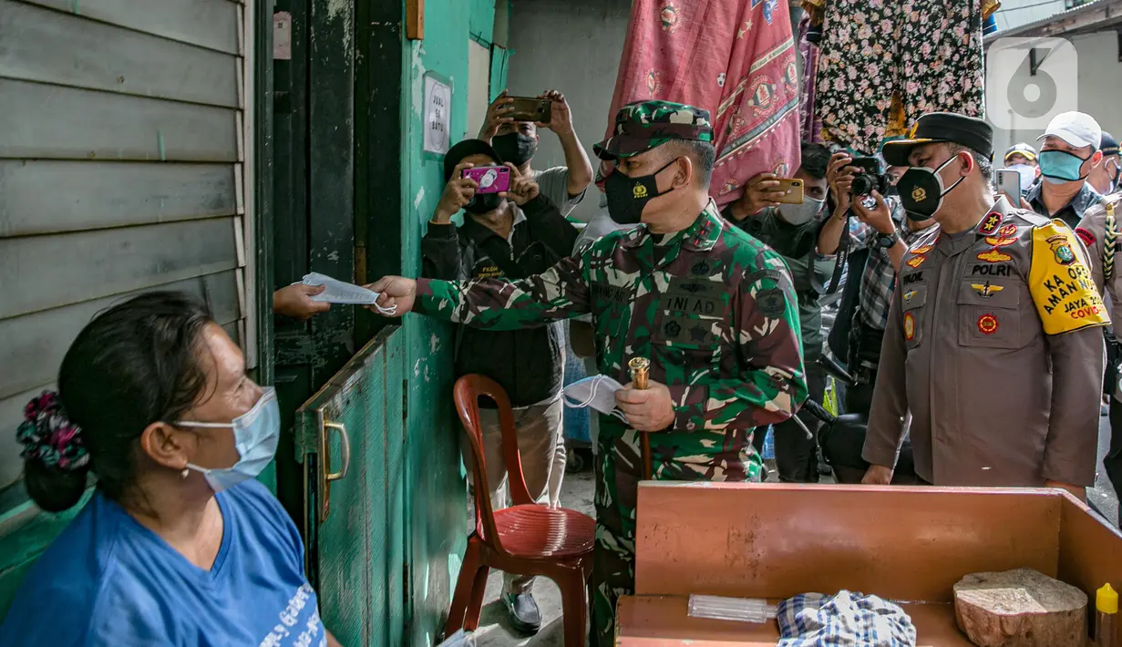 Pangdam Jaya Mayjen TNI Dudung Abdurrachman (tengah) bersama Kapolda Metro Jaya Irjen Pol Fadil Imran membagikan masker ke warga di Sunter Muara, Tanjung Priok, Jakarta, Selasa (9/2/2021). Kegiatan ini untuk menyadarkan masyarakat akan pentingnya penggunaan masker. (Liputan6.com/Faizal Fanani)