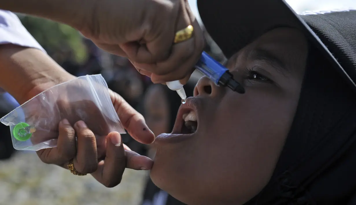 Seorang anak menerima imunisasi polio dari petugas medis saat berlangsung vaksinasi massal di Sigli Town Square,  Pidie, Aceh, Senin (28/11/2022). Kementerian Kesehatan melakukan vaksinasi massal sebanyak 1.000 anak dari target target 9.940 anak. (AP Photo/Riska Munawarah)