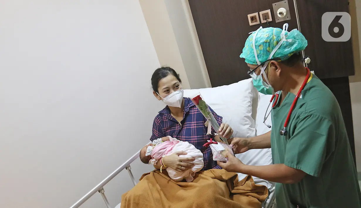 Dokter anak Pulung Silalahi memberikan bunga dan kue ke pasien rawat inap di Rumah Sakit Ibu dan Anak Tambak, Jakarta, Selasa (22/12/2020). Pemberian bunga dan kue kepada pasien rawat inap dan pasien yang kontrol dilakukan untuk memperingati perayaan Hari Ibu. (Liputan6.com/Herman Zakharia)