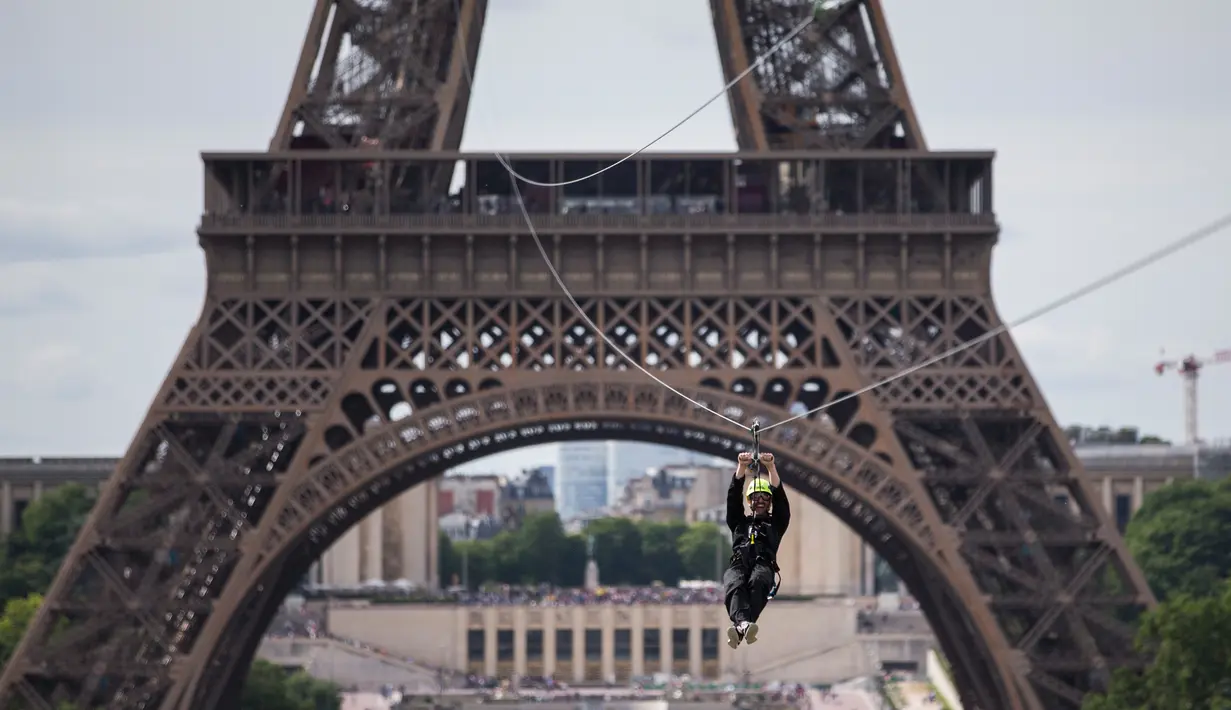 Seorang wanita meluncur dari Menara Eiffel di Paris dengan menggunakan peralatan flying fox, 5 Juni 2017. Kesempatan ini dibuka untuk umum jelang turnamen tenis French Open agar dapat merasakan bagaimana kecepatan bola tenis (AP Photo/Kamil Zihnioglu)
