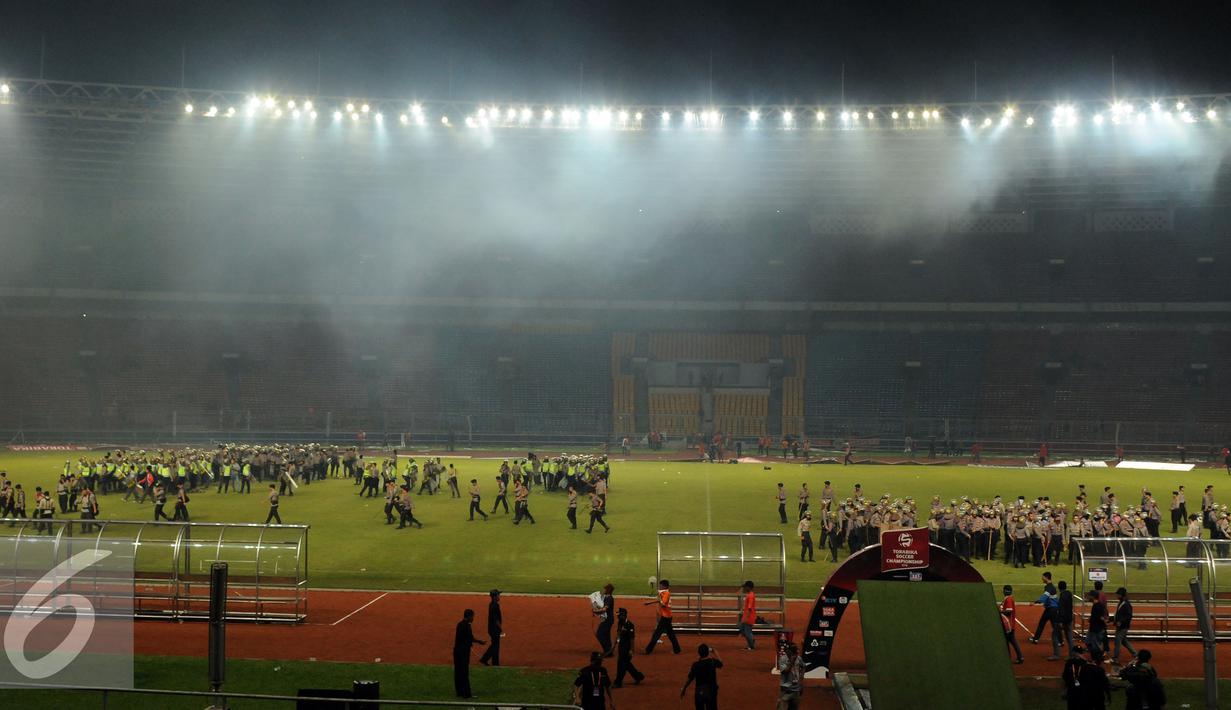 Petugas kepolisian menguasai lapangan setelah terlibat bentrok dengan suporter saat laga Persija melawan Sriwijaya FC di Stadion GBK Jakarta, Jumat (24/6). Laga dihentikan di menit 81.(Liputan6.com/Helmi Fithriansyah)