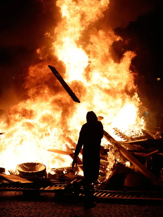 Demonstran membakar barang-barang saat kerusuhan menentang kenaikan harga bahan bakar di Paris, Prancis, Sabtu (24/11). Lebih dari 100.000 orang mengambil bagian dalam sekitar 1.600 aksi protes di seluruh Prancis. (AP Photo/Kamil Zihnioglu)