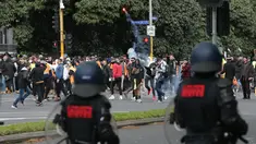 Seorang demonstran melemparkan suar saat protes terhadap peraturan Covid-19 di Melbourne (21/9/2021). Ribuan orang membuat kekacauan dan bentrok dengan polisi di kota dan mengambil alih jalan raya utama Melbourne saat protes terjadi. (AFP/STR)