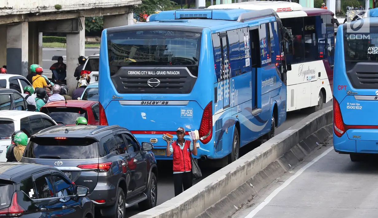 Pedagang asongan menjajakan barang dagangannya di persimpangan lampu merah di Jakarta, Jumat (22/2). Keahlian yang terbatas menyebabkan sebagian orang harus bekerja di tengah padatnya kendaraan Ibukota. (Liputan6.com/Immanuel Antonius)
