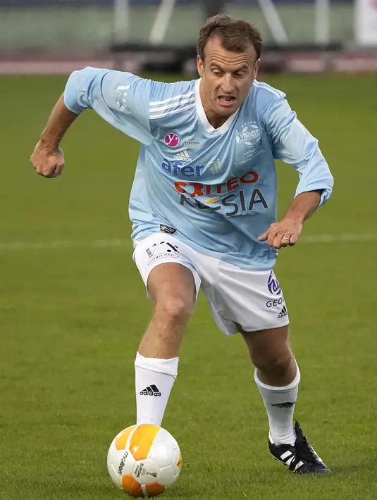 Presiden Prancis Emmanuel Macron menggiring bola saat bermain pada laga amal peringatan 50 tahun Varietes Club di Stadion Leo Lagrange, Poissy, Prancis, Kamis (14/10/2021). Macron dan mantan manajer Arsenal Arsene Wenger bermain laga amal untuk Yayasan Rumah Sakit. (AP Photo/Michel Euler)