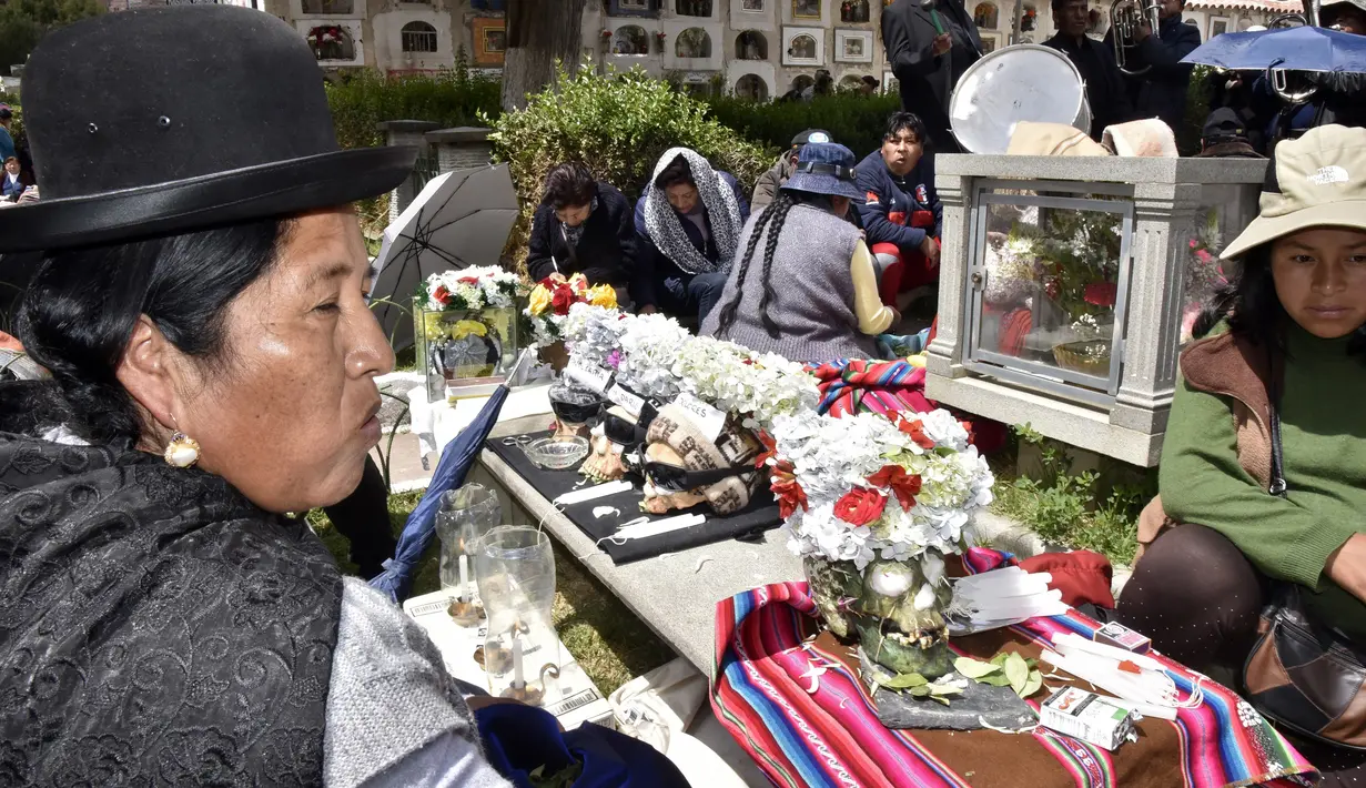 Wanita pribumi Aymara menyembah tengkorak manusia selama Festival Natitas di pemakaman La Paz, Bolivia pada 8 November 2018.  Festival ini adalah ritual mengerikan di mana tengkorak manusia (natitas) dibawa ke pemakaman untuk dihormati. (AIZAR RALDES/AFP)