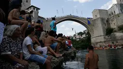 Penonton menyaksikan seorang peserta melompat dari Jembatan Old Mostar pada kompetisi menyelam tradisional ke-452 di Mostar, Bosnia, 29 Juli 2018. Ini merupakan kompetisi selam tahunan yang menjadi salah satu daya tarik Bosnia. (AP/Amel Emric)