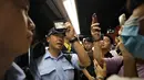 Seorang perwira polisi menunjukkan kartu anggotanya setelah pemrotes memintanya di sebuah stasiun kereta bawah tanah di Hong Kong (30/7/2019). Para Pengunjuk rasa telah mengganggu layanan kereta bawah tanah pada pagi hari. (AP Photo/Vincent Yu)