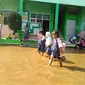 Banjir di ruang kelas dan guru kini mulai surut. Siswa bersama guru sibuk membersihkan lumpur di ruang kelas.