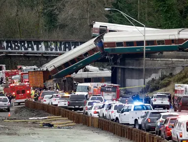 Kereta Amtrak yang terjatuh dari jembatan dan menimpa kendaraan-kendaraan terlihat di jalan raya di Interstate di DuPont, Washington, AS (18/12). Diketahui 13 dari 14 gerbong kereta jatuh ke jalan raya. (AP Photo / Elaine Thompson)