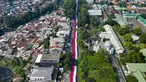 Foto udara ini memperlihatkan sekitar 3.500 orang yang berpartisipasi dalam pawai membawa bendera Indonesia sepanjang 500 meter di Jalan Sudirman Bogor, Jawa Barat, Minggu,  9 Agustus 2026. (AFP/ Aditya Aji)